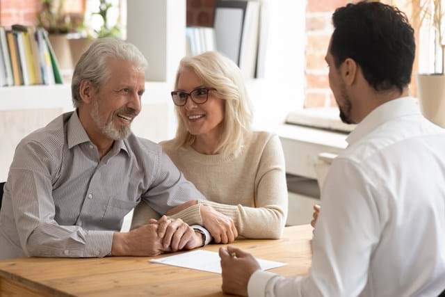 A man and woman engage in conversation with a financial advisor in Sunbury, sharing smiles and attentive expressions.
